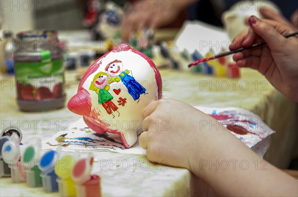 Children at an event painting white piggy banks