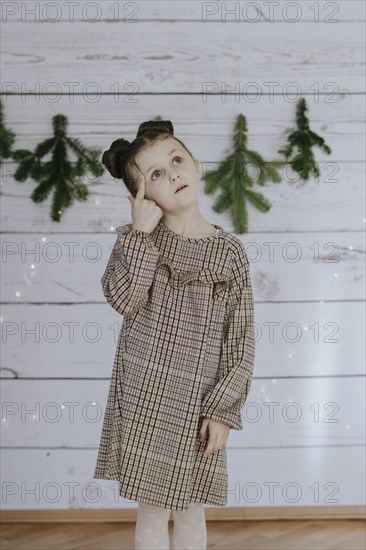 Girl thinks in front of a Christmas backdrop