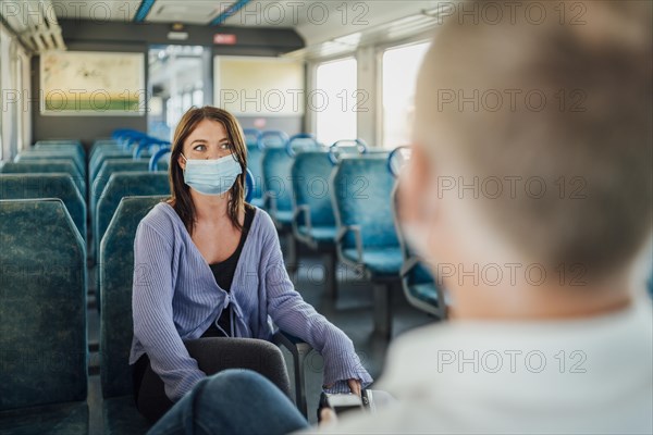 A couple of travelers wearing mask chatting in a train