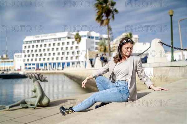 Young woman sitting by the marina in Faro