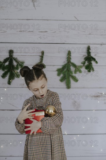 Girl with Christmas present in front of a Christmas backdrop