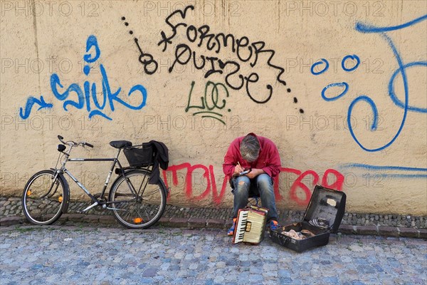 Sitting street musician with harmonium making notes