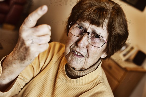 Angry senior citizen threatens with her raised index finger