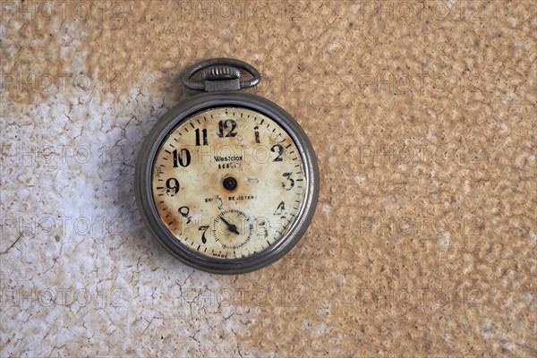 Old pocket watch without hands on stone base with patina