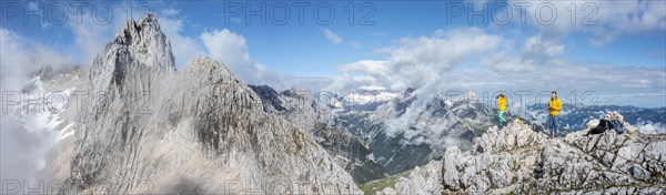 Two hikers in front of alpine panorama