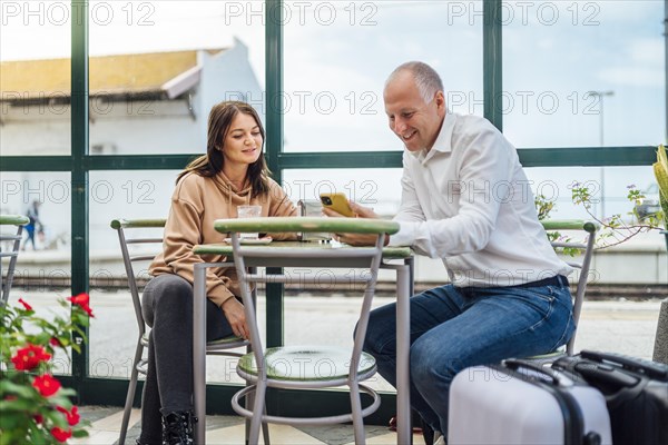 A couple of travelers drinking coffee and checking something on the phone