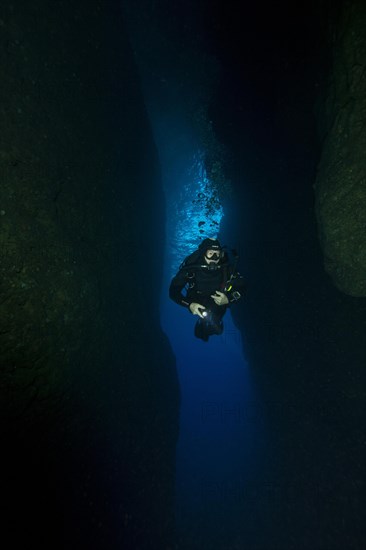 Diver swims diving through tunnel from inland sea of Gozo into passage to open sea
