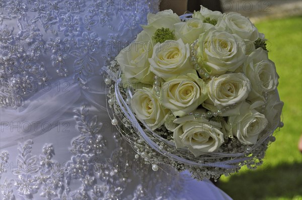 Wedding dress and bridal bouquet of yellow roses and pearl necklace