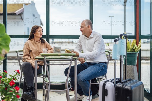 A couple of travelers drinking coffee and checking something on the phone