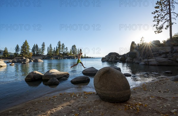 Young man in swimming trunks jumps from stone to stone