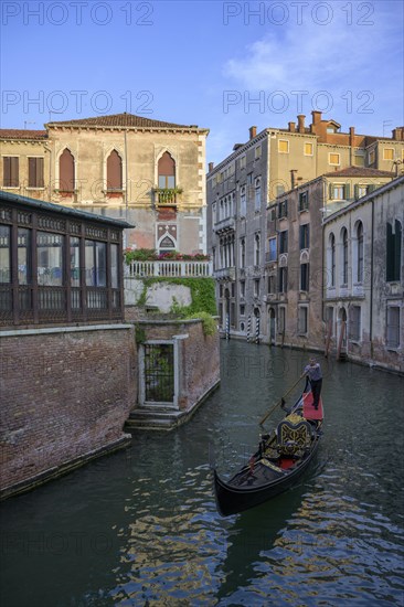 Gondola in a small canal and evening light on the houses