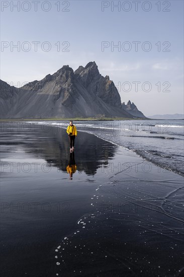 Young woman with rain jacket walking on beach