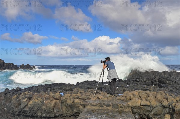 Photographer taking pictures in strong waves at the sea