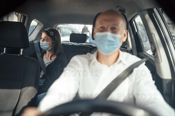 Taxi driver in a mask with a female client on the back seat wearing mask