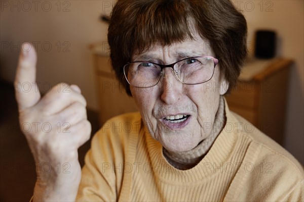 Angry senior citizen threatens with her raised index finger