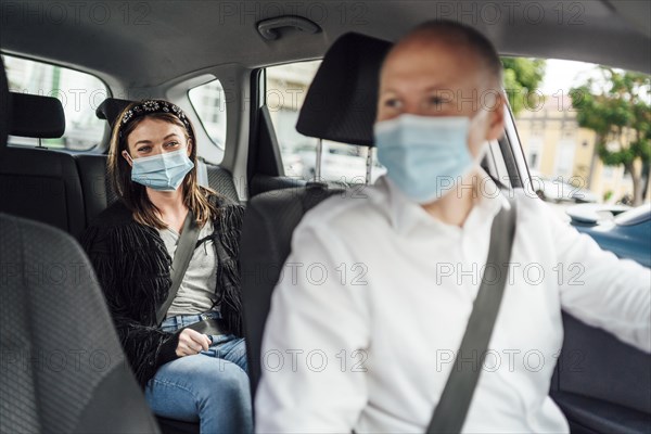 Taxi driver in a mask with a female client on the back seat wearing mask