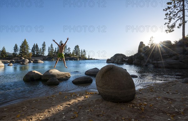 Young man in swimming trunks jumps in the air