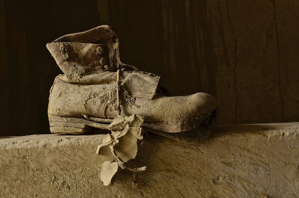 Work shoe on wall with lump of clay on the lace