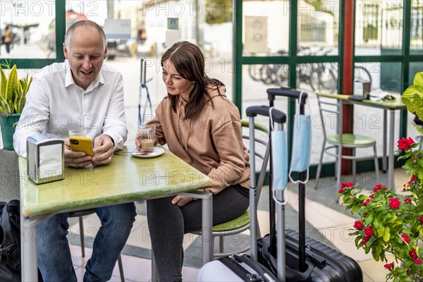 A couple of travelers drinking coffee and checking something on the phone