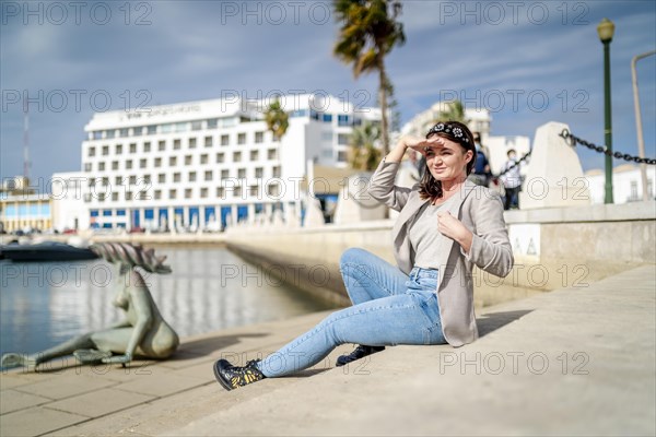 Young woman sitting by the marina in Faro