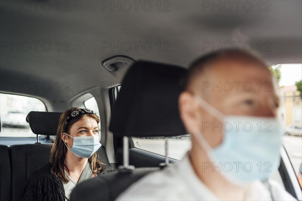 Taxi driver in a mask with a female client on the back seat wearing mask