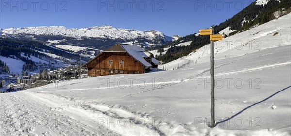 Winter hiking trail with alpine farm high above Soerenberg