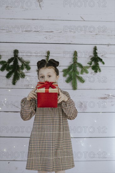 Girl with Christmas present in front of a Christmas backdrop