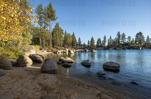 Young man in swimming trunks on round stones in the water