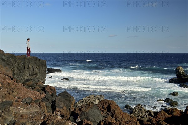 Hiker standing on rocky coast by the sea