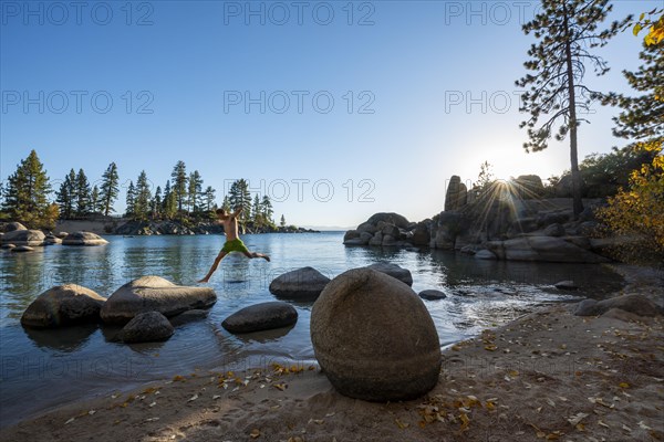 Young man in swimming trunks jumps from stone to stone