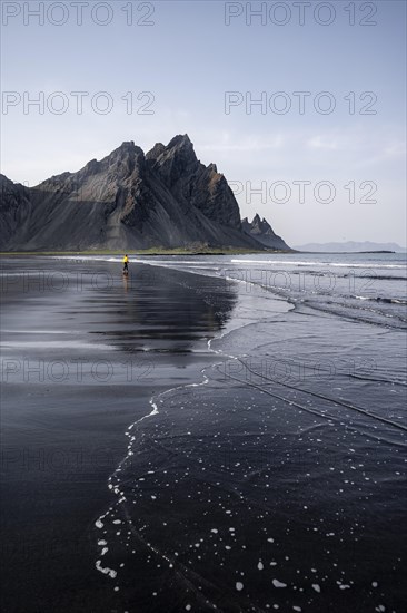 Young woman with rain jacket walking on beach