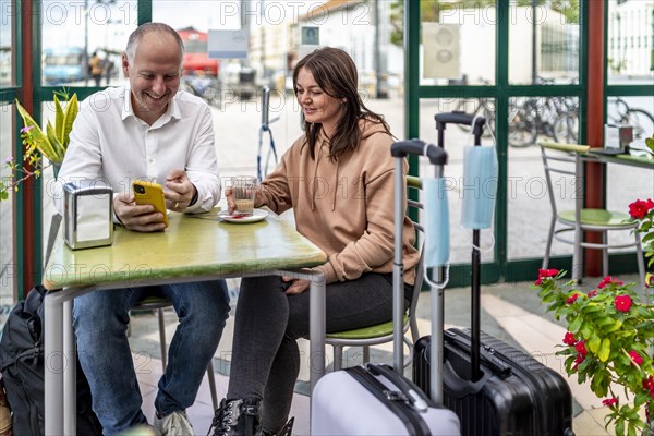 A couple of travelers drinking coffee and checking something on the phone