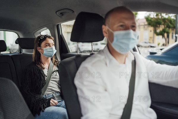 Taxi driver in a mask with a female client on the back seat wearing mask