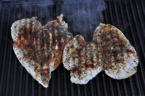 Three heart-shaped chicken breasts on the grill