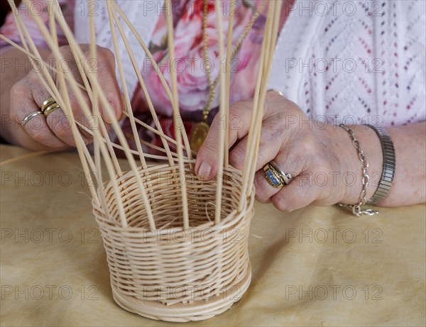 Hands of an 86-year-old senior citizen in a nursing home weaving a basket