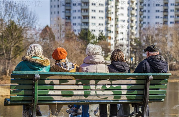 Senior citizens with a carer sitting on a wooden bench at the Segeluchbecken in the Maerkisches Viertel