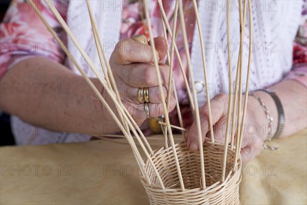 Hands of an 86-year-old senior citizen in a nursing home weaving a basket