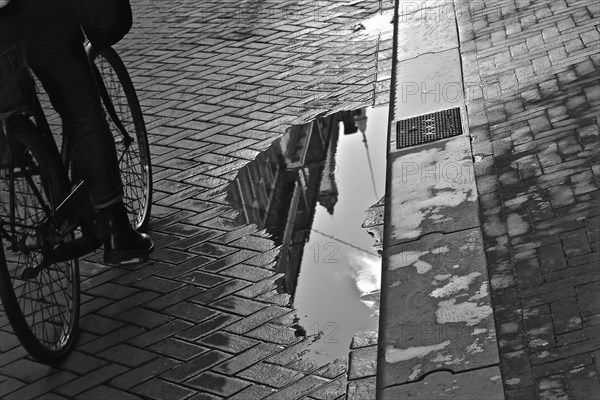 Cyclist after rain with reflection of a puddle