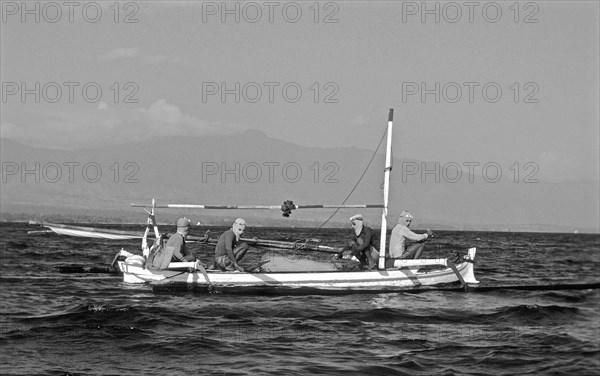 Shell divers with masks protected from the sun's rays on a wooden boat