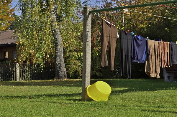 Laundry hung on line with yellow bowl in autumnal garden