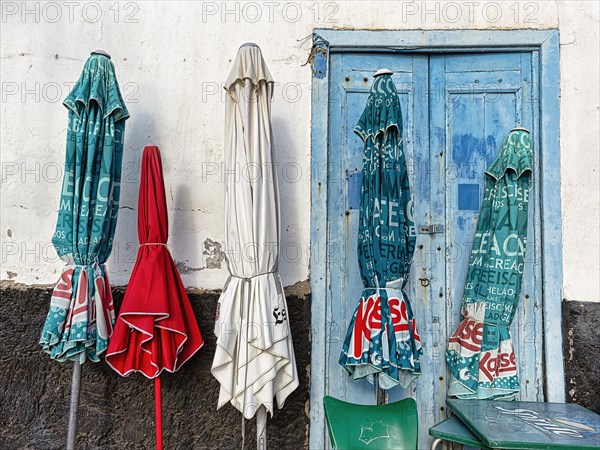 Five closed parasols in front of house wall