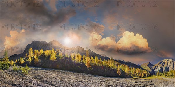 Glowing autumnal mountain forest below the Lamsenjoch massif with bizarre cloudy sky