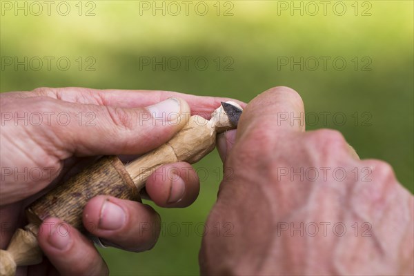 Man carving a small wooden figure