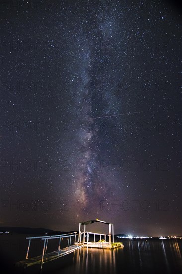 Night view of the Milky Way with illuminated jetty in the foreground