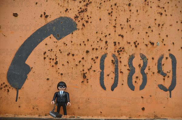 Black figure with telephone receiver and area code of Munich painted on orange metal container