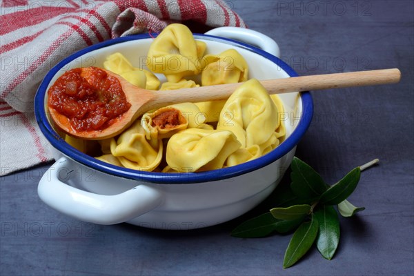 Pasta in pot and cooking spoon with tomato sauce