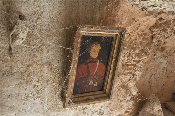 Golden picture frame with cobwebs on clay wall