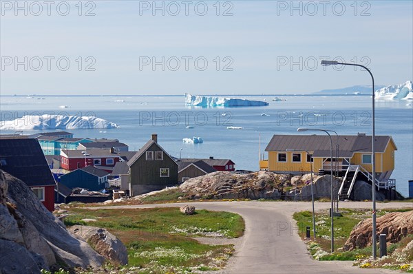 Narrow road and simple dwellings on the edge of an iceberg-covered bay