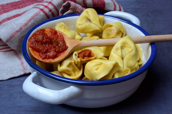 Pasta in pot and cooking spoon with tomato sauce