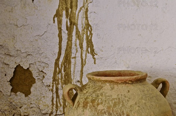 Old clay jug in front of dilapidated wall